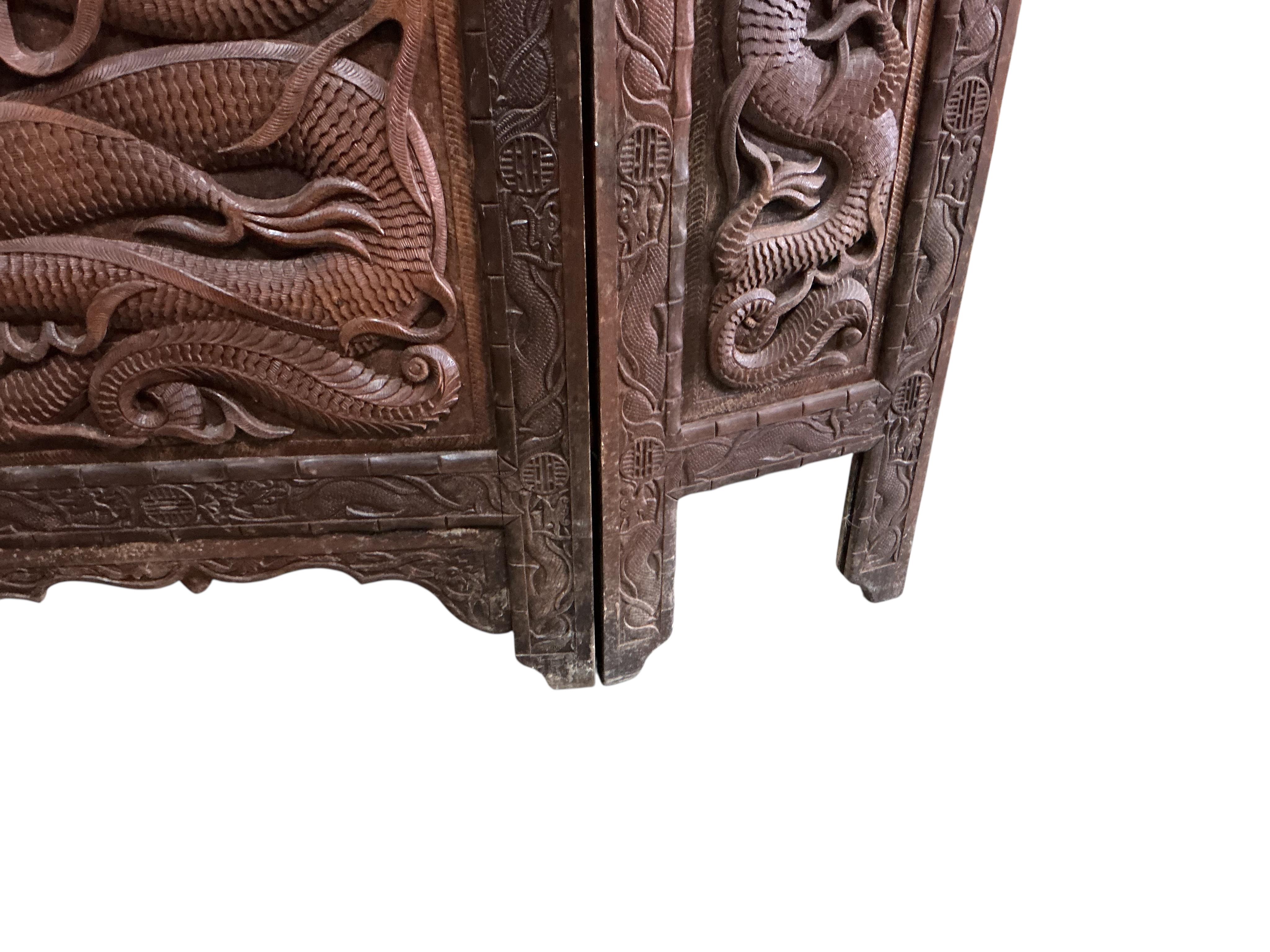 A Far Eastern carved hardwood triple panel firescreen and a wall mirror, mirror height 90cm